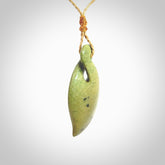 Single twist pendant. Hand carved from rare New Zealand flower jade this is a beautiful pounamu pendant. The cord is hand plaited in a tan colour and is length adjustable. It has a floret in gold. It is a delicate and very beautiful greenstone pendant. For sale online by NZ Pacific.